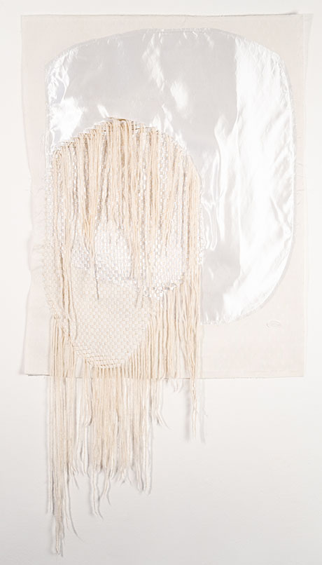 Textured art piece featuring a shiny, reflective shape atop cascading white yarn strands, set against a soft, neutral background.