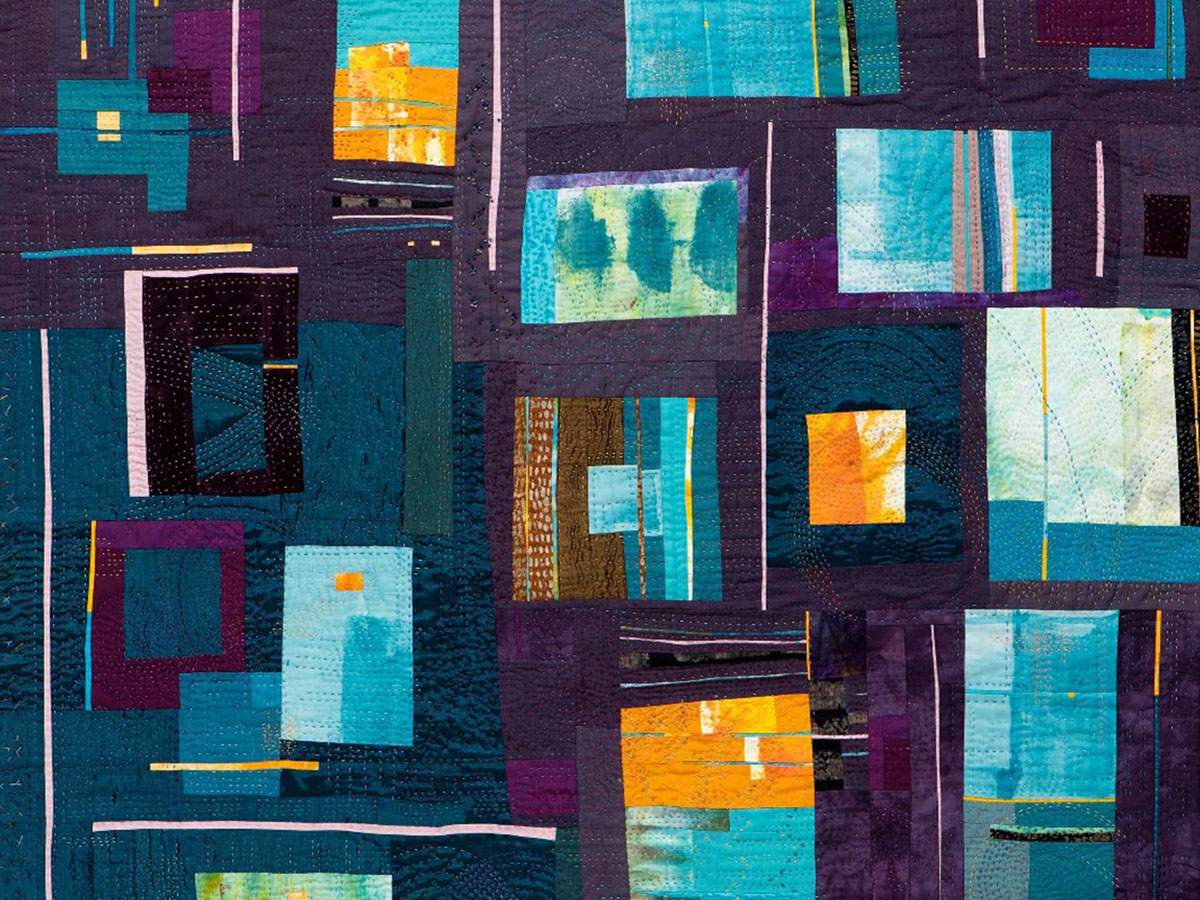 A vibrant quilt featuring a patchwork of teal, blue, and purple fabrics, with geometric shapes and textured stitching.
