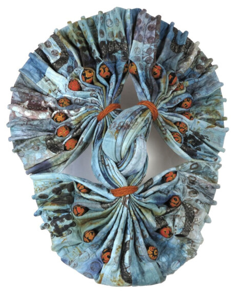 A colorful, intricately folded textile art piece featuring blue tones and orange accents, resembling a floral design. A colorful, intricately folded textile art piece featuring blue tones and orange accents, resembling a floral design.
