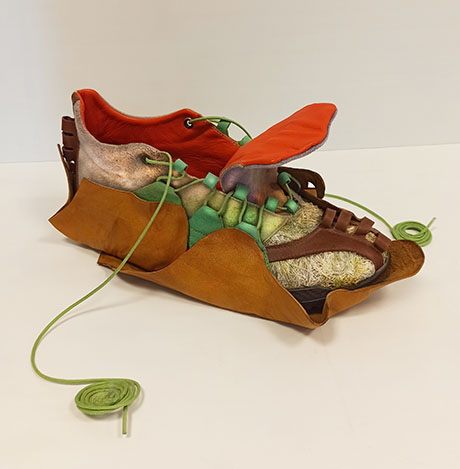A uniquely designed shoe featuring textured brown, green, and orange materials, resembling organic elements and adorned with vibrant laces. A uniquely designed shoe featuring textured brown, green, and orange materials, resembling organic elements and adorned with vibrant laces.