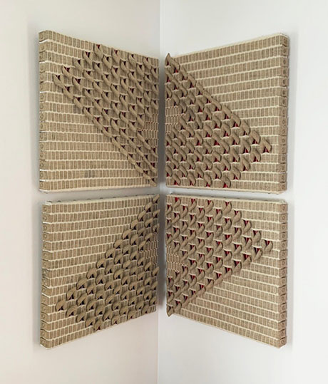 Art installation featuring four canvases in a corner, showcasing textured patterns with a cream background and red accents. Art installation featuring four canvases in a corner, showcasing textured patterns with a cream background and red accents.