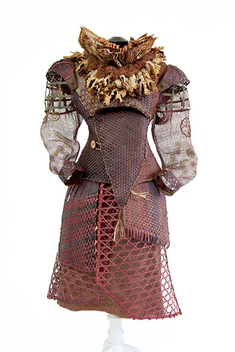 A unique, avant-garde dress featuring textured burgundy fabrics, intricate layering, and a dramatic floral collar. A unique, avant-garde dress featuring textured burgundy fabrics, intricate layering, and a dramatic floral collar.