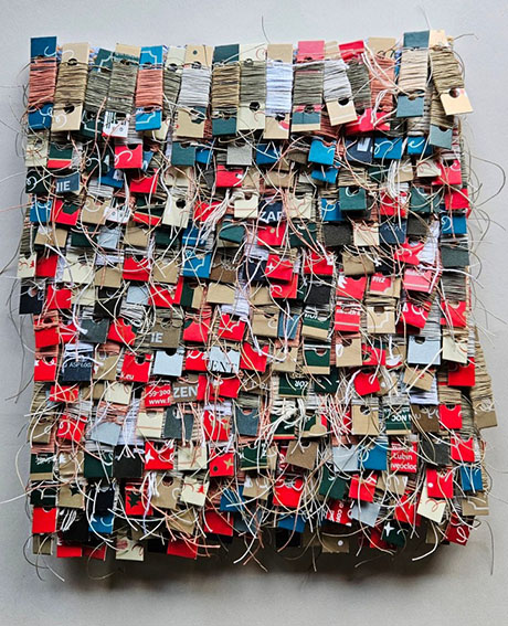 A vibrant textile artwork made of assorted thread spools, color tags, and strings arranged in an intricate grid pattern. A vibrant textile artwork made of assorted thread spools, color tags, and strings arranged in an intricate grid pattern.