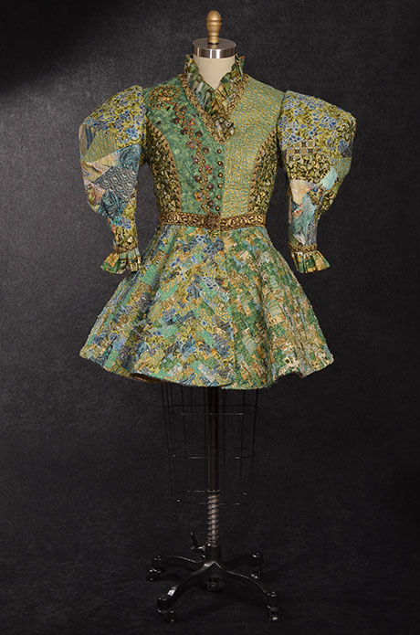 A vibrant, patterned green dress displayed on a mannequin, featuring puffed sleeves and ornate buttons down the front. A vibrant, patterned green dress displayed on a mannequin, featuring puffed sleeves and ornate buttons down the front.