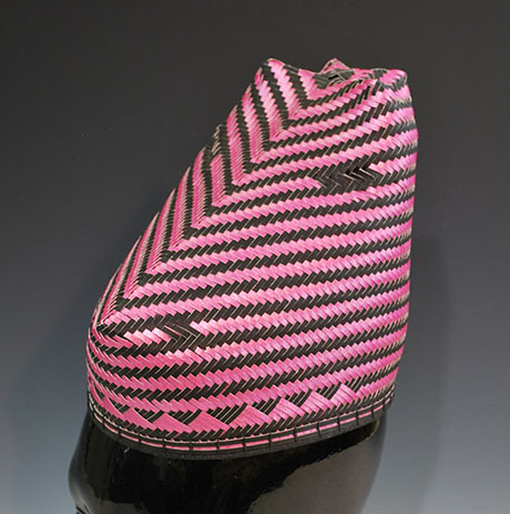 A vibrant pink and black woven hat with a chevron pattern, showcasing intricate craftsmanship and unique design. A vibrant pink and black woven hat with a chevron pattern, showcasing intricate craftsmanship and unique design.