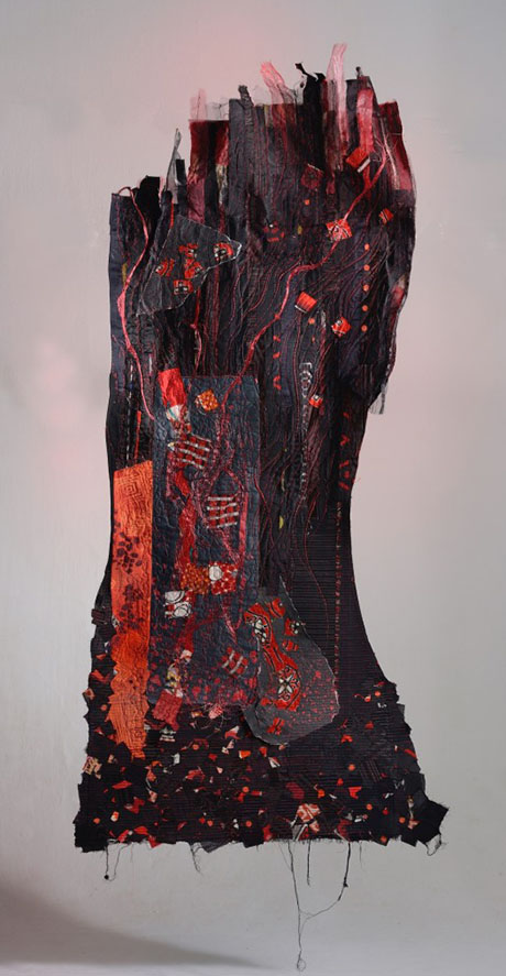 A textured textile artwork featuring vibrant reds and blacks, with intricate patterns and stitched details, resembling an abstract landscape. A textured textile artwork featuring vibrant reds and blacks, with intricate patterns and stitched details, resembling an abstract landscape.