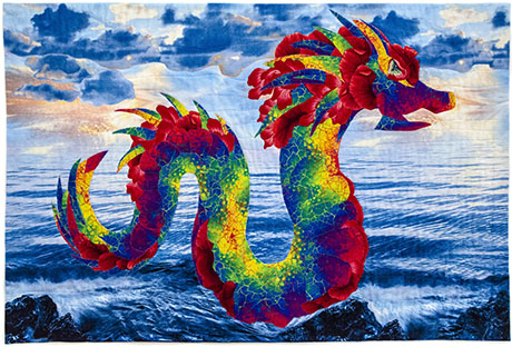 A vibrant quilt featuring a colorful dragon against a serene ocean backdrop with clouds and rocks.