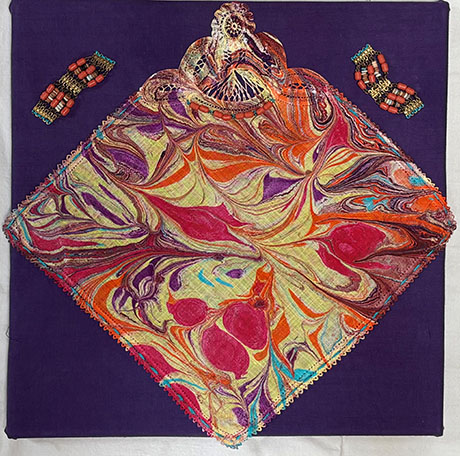 A vibrant marbled cloth with swirling patterns of red, orange, purple, and blue is centrally placed on a dark purple background. Two ornate bracelets with red beads flank the cloth, creating a colorful and artistic display.