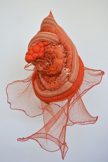 An intricate, coral-like sculptural artwork in vibrant orange hues, features layered textures and mesh elements. It conveys an organic, flowing elegance.