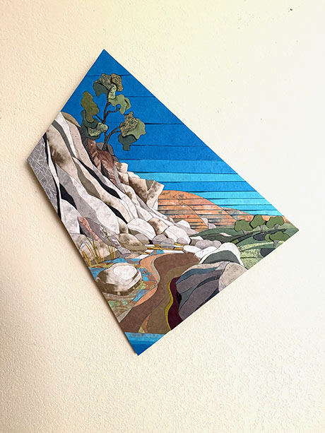 A vibrant landscape painting, tilted diamond-shaped, depicts a rocky path through hills and trees under a bright blue sky, evoking a serene outdoor scene.