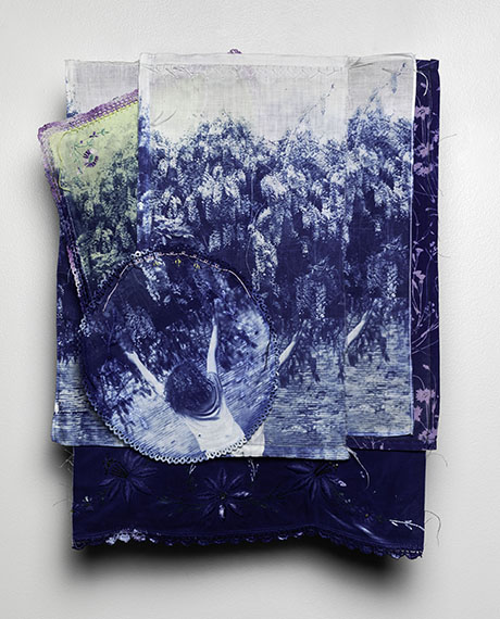 Textile art piece with layered blue and purple fabrics. Central image shows a child with raised arms, surrounded by trees. Dreamy and abstract.