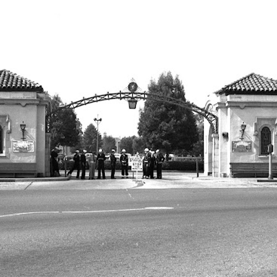 Black-and-white film negative shows sailors, officers and military police at a gate to the U.S. Naval Training Center.