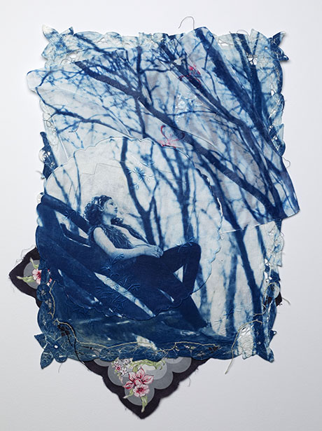 A person sits pensively against a tree in a blue monochrome image. Surrounding branches frame him, conveying a contemplative, serene mood. Floral lace edges.