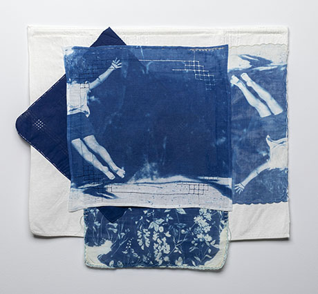 A layered textile artwork featuring cyanotypes of a person diving and floral patterns. The dominant blue and white tones convey a serene, artistic mood.