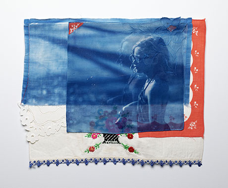 A layered textile artwork with a blue translucent image of a person on a red and white embroidered fabric. The collage conveys a dreamy, introspective tone.