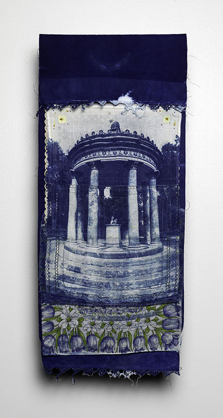Fabric artwork with a cyanotype of a pillared temple, framed by deep blue tones. Below, a pattern of flowers and fruits adds texture and contrast.