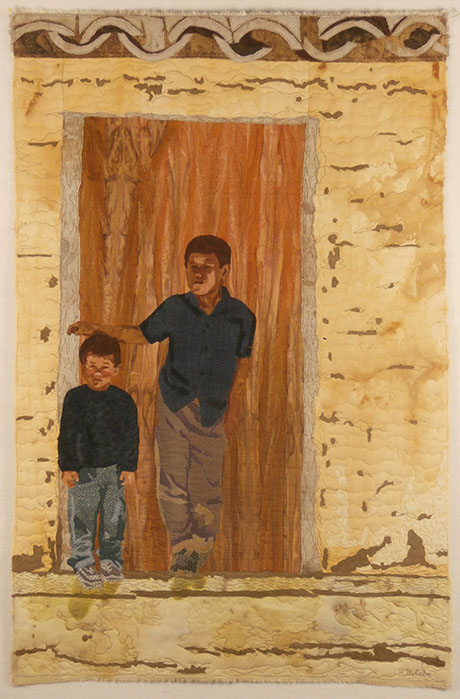 Textile artwork depicting two boys standing in front of a wooden door set in a textured, beige stone wall, by Kathleen McCabe.